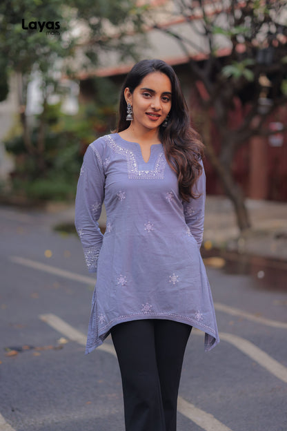 Woman wearing a light purple embroidered top and black pants outdoors from layas marts